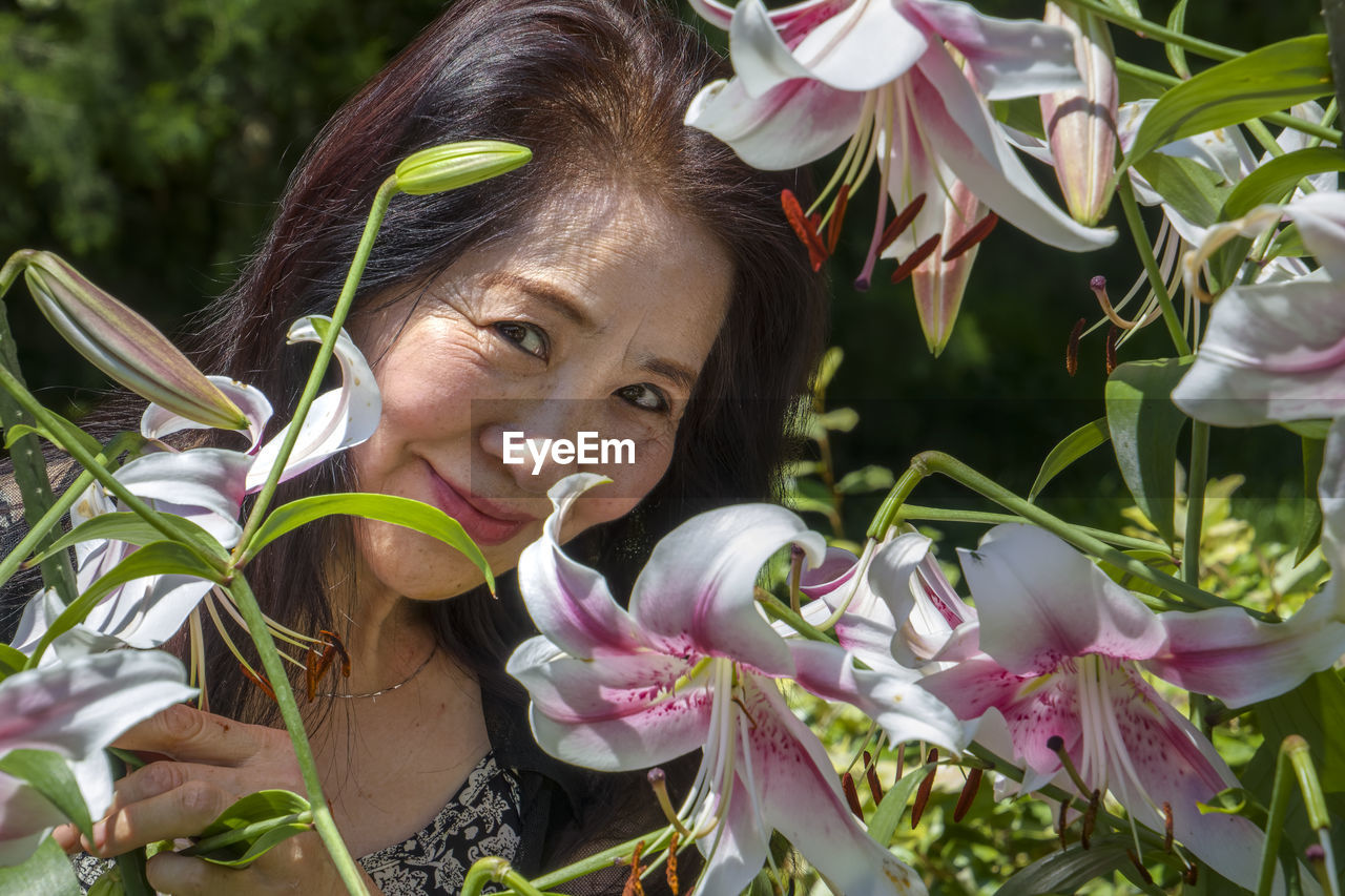 PORTRAIT OF WOMAN WITH PINK FLOWERS ON PLANT