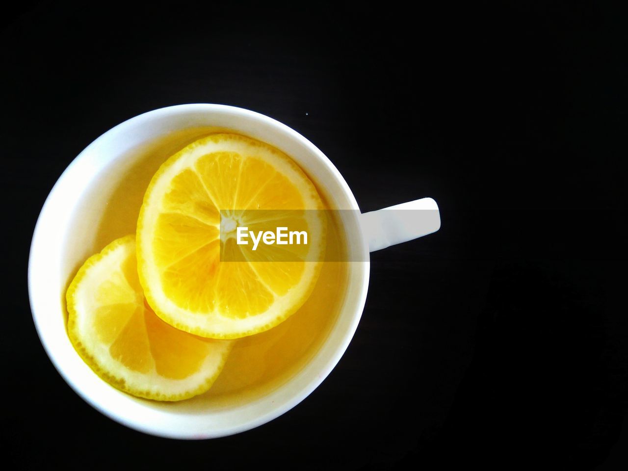 Lemon slices in coffee cup over black background