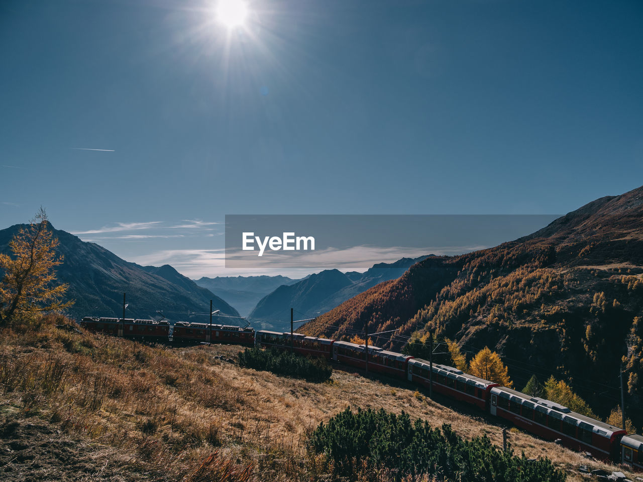 Train passing by mountains on sunny day