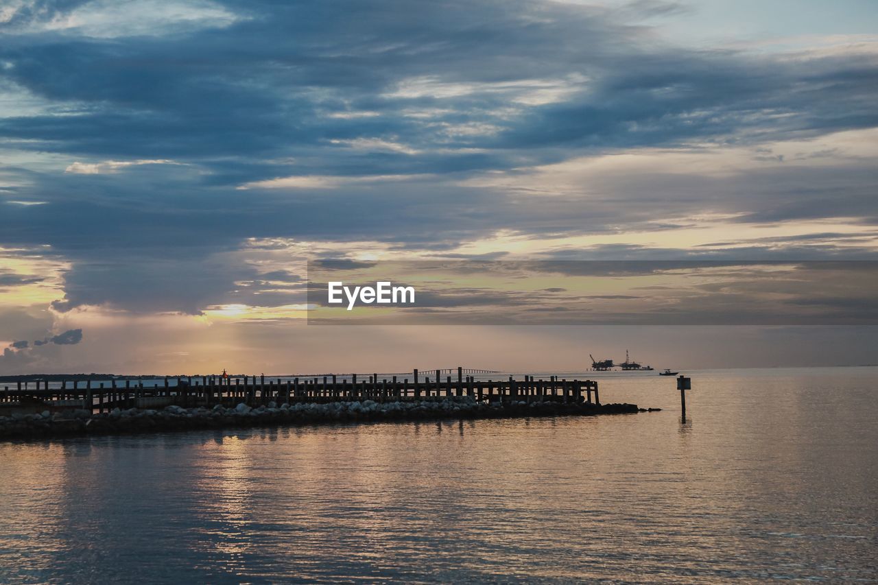 Pier over sea against sky during sunset