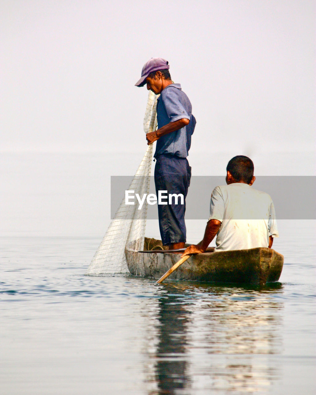 REAR VIEW OF PEOPLE ON SEA AGAINST SKY