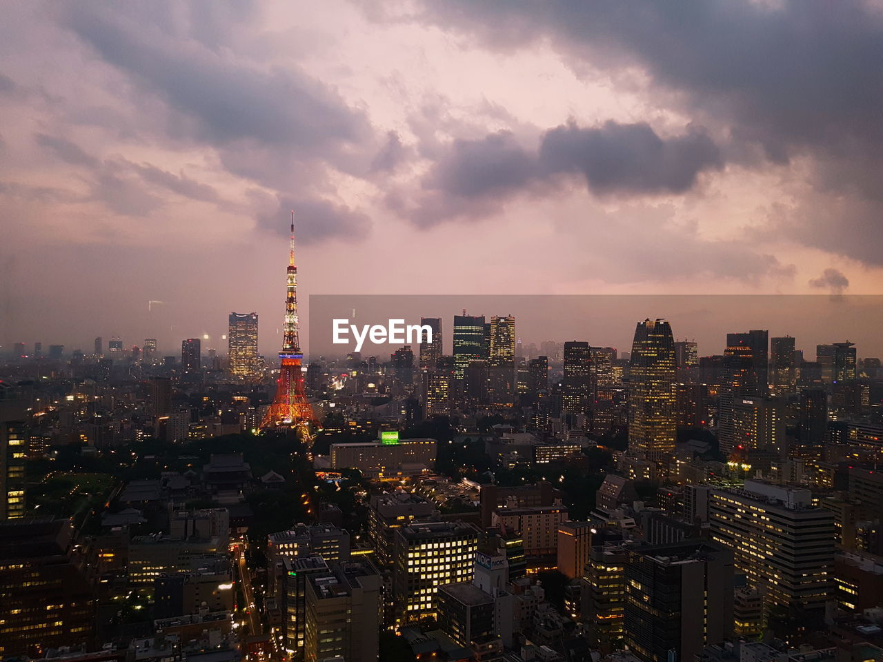 Illuminated cityscape against cloudy sky