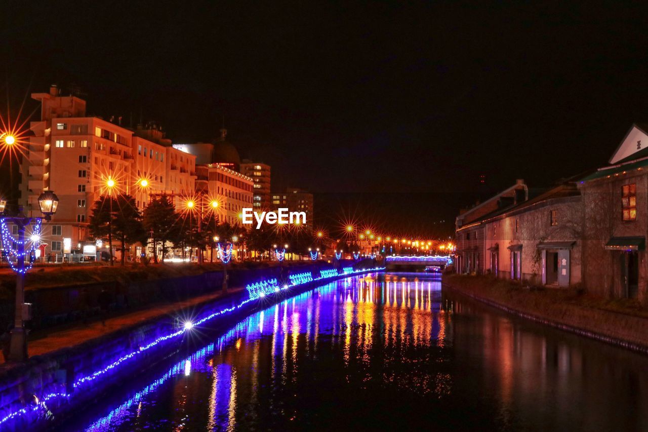 ILLUMINATED BUILDINGS BY CANAL AT NIGHT