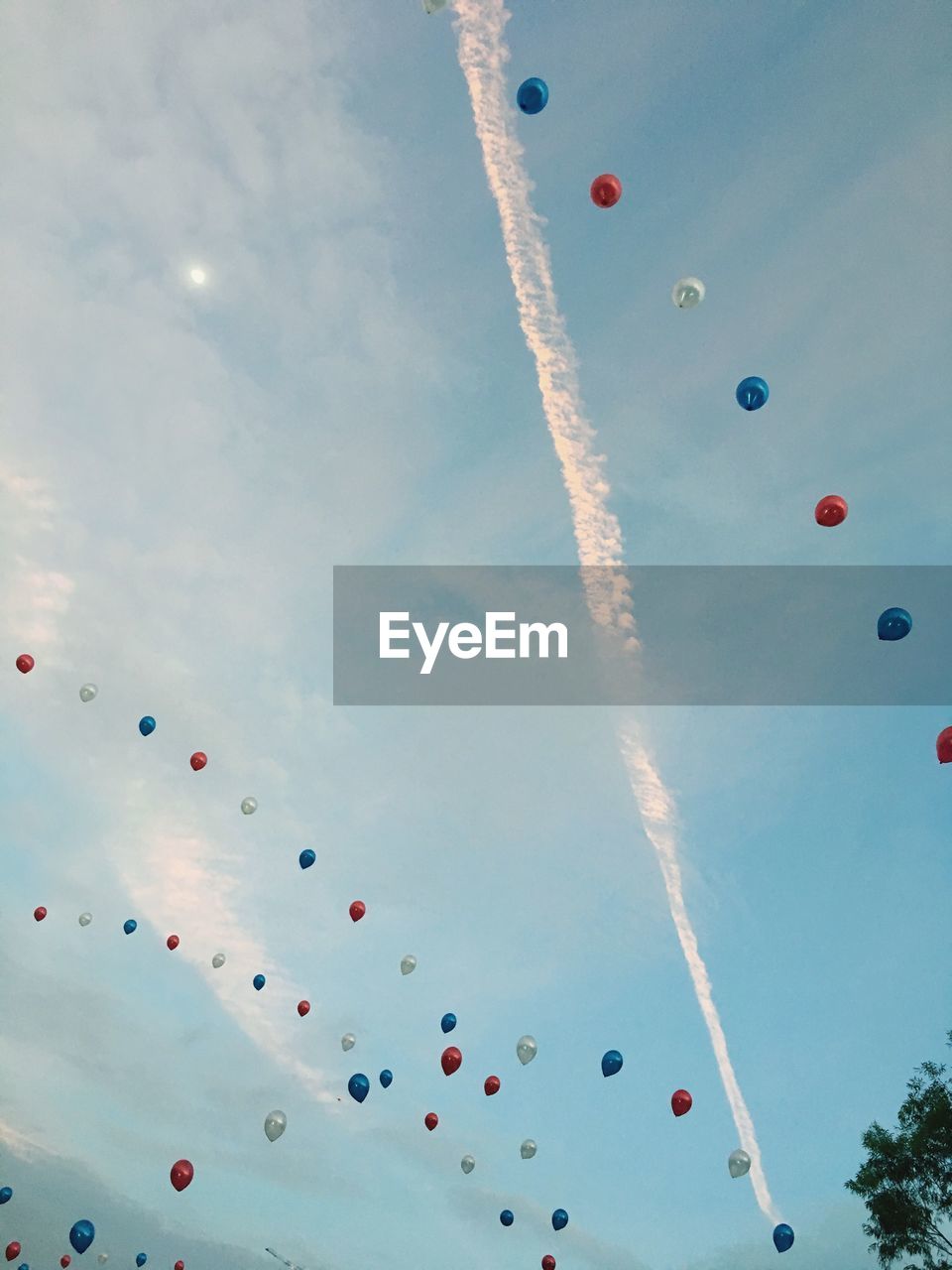 Low angle view of balloons flying against cloudy sky