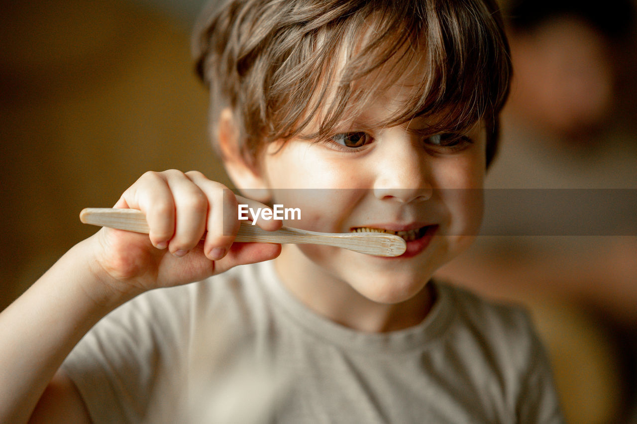 The boy brushes his teeth with a toothbrush made of ecological material