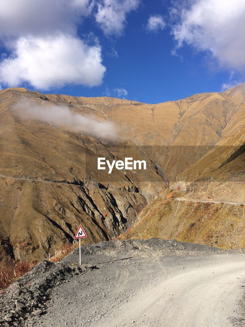 Scenic view of road by mountains against sky