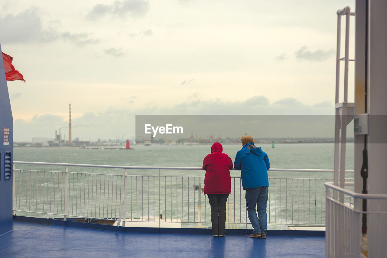 Rear view of people in boat on sea against sky