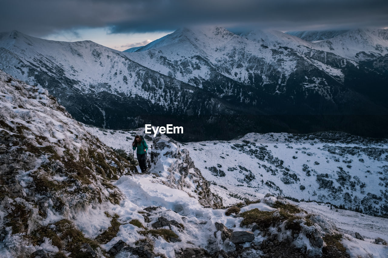 Woman hiking on snowcapped mountain during storm cloud