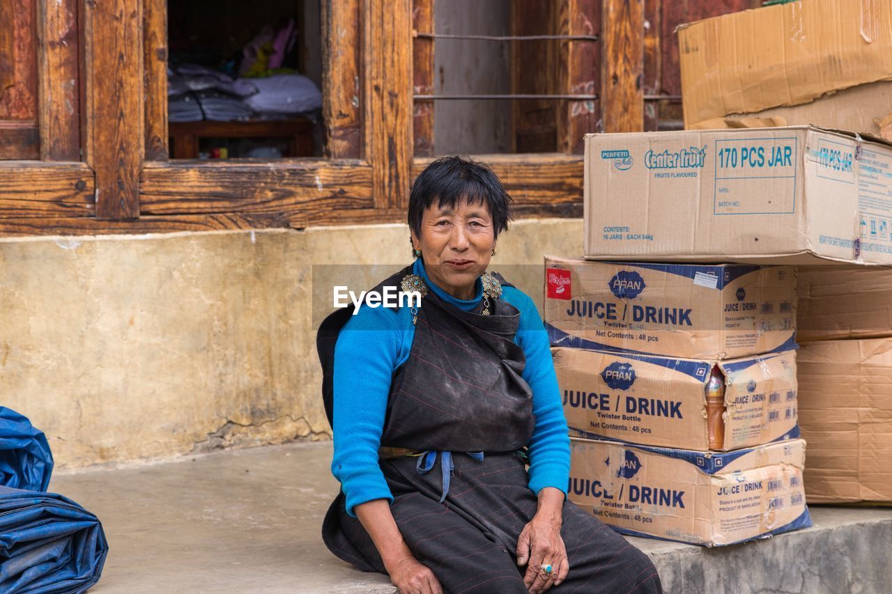 PORTRAIT OF A SMILING YOUNG WOMAN SITTING OUTDOORS