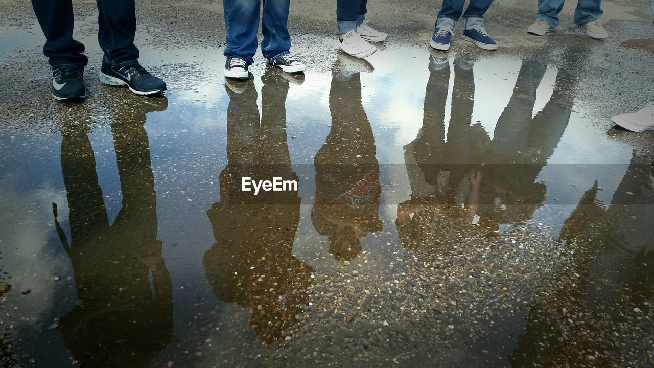 LOW SECTION OF PEOPLE STANDING ON PUDDLE
