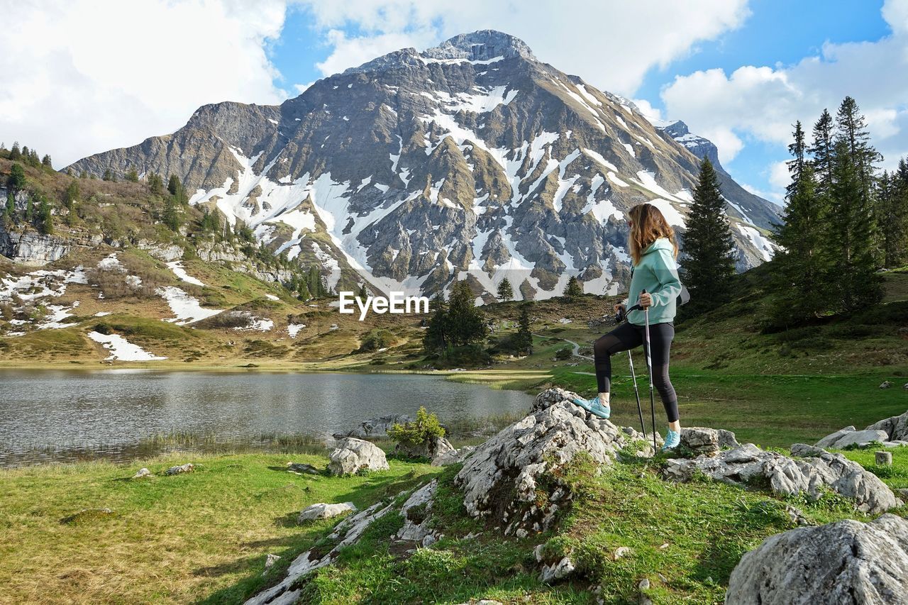 Woman standing on rocks against mountains by the alpine lake in austria