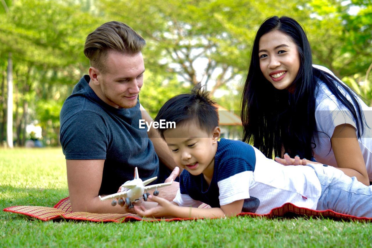 Family lying on grassy field at park