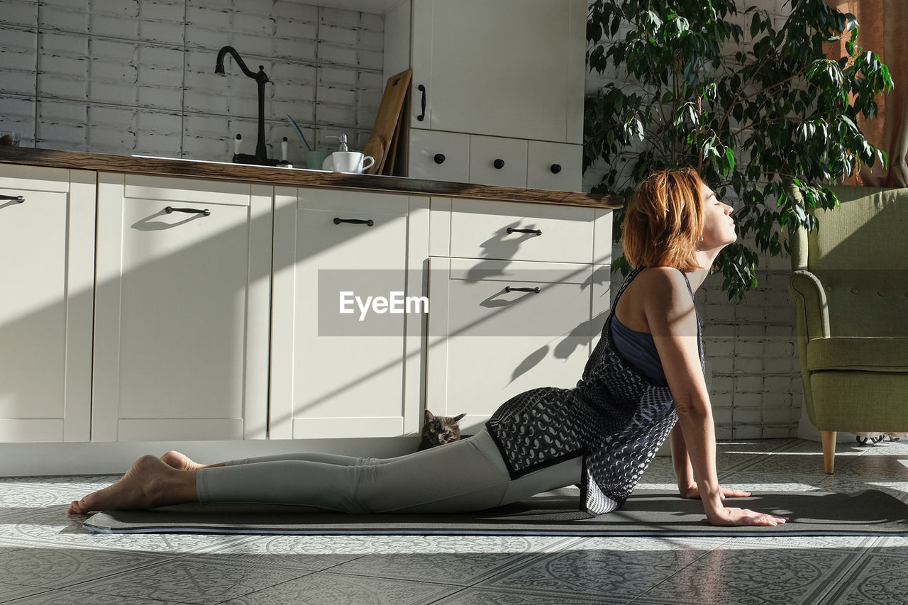 Middle aged woman practicing meditation at home, lady in yoga pose doing yoga for mental balance 