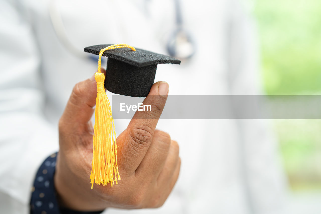 cropped hand of woman wearing mortarboard