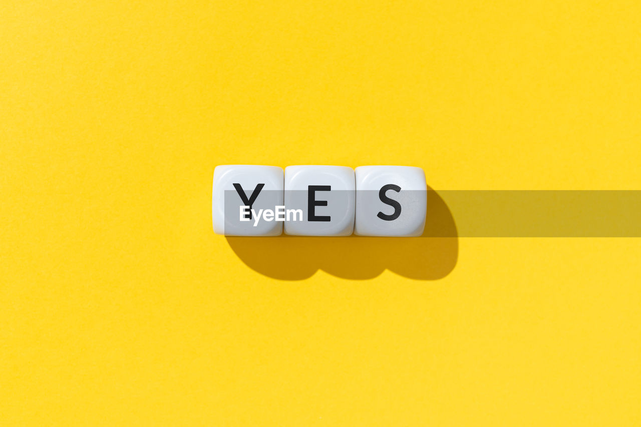 Yes word on white cube blocks isolated on yellow background