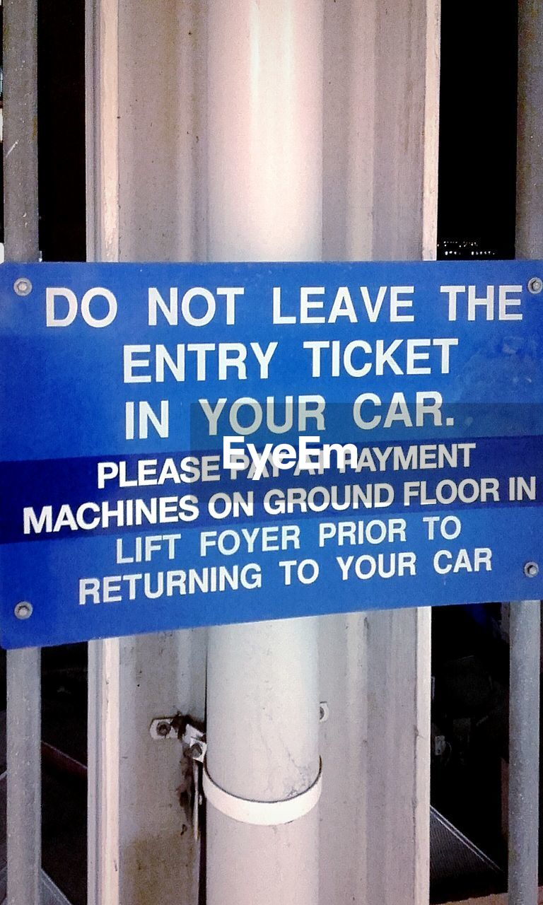 CLOSE-UP OF WARNING SIGN ON BLUE METAL