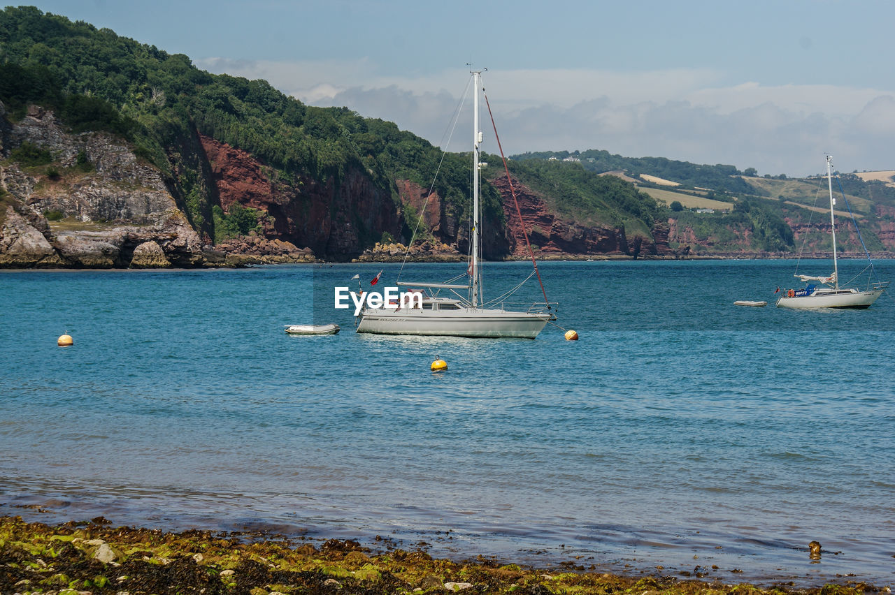 Sailboats in sea against sky