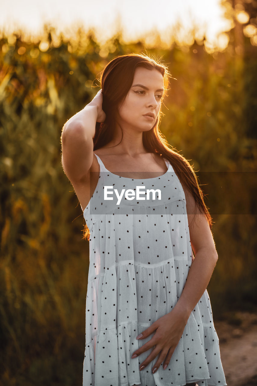 Young beautiful woman in white dress in corn field.