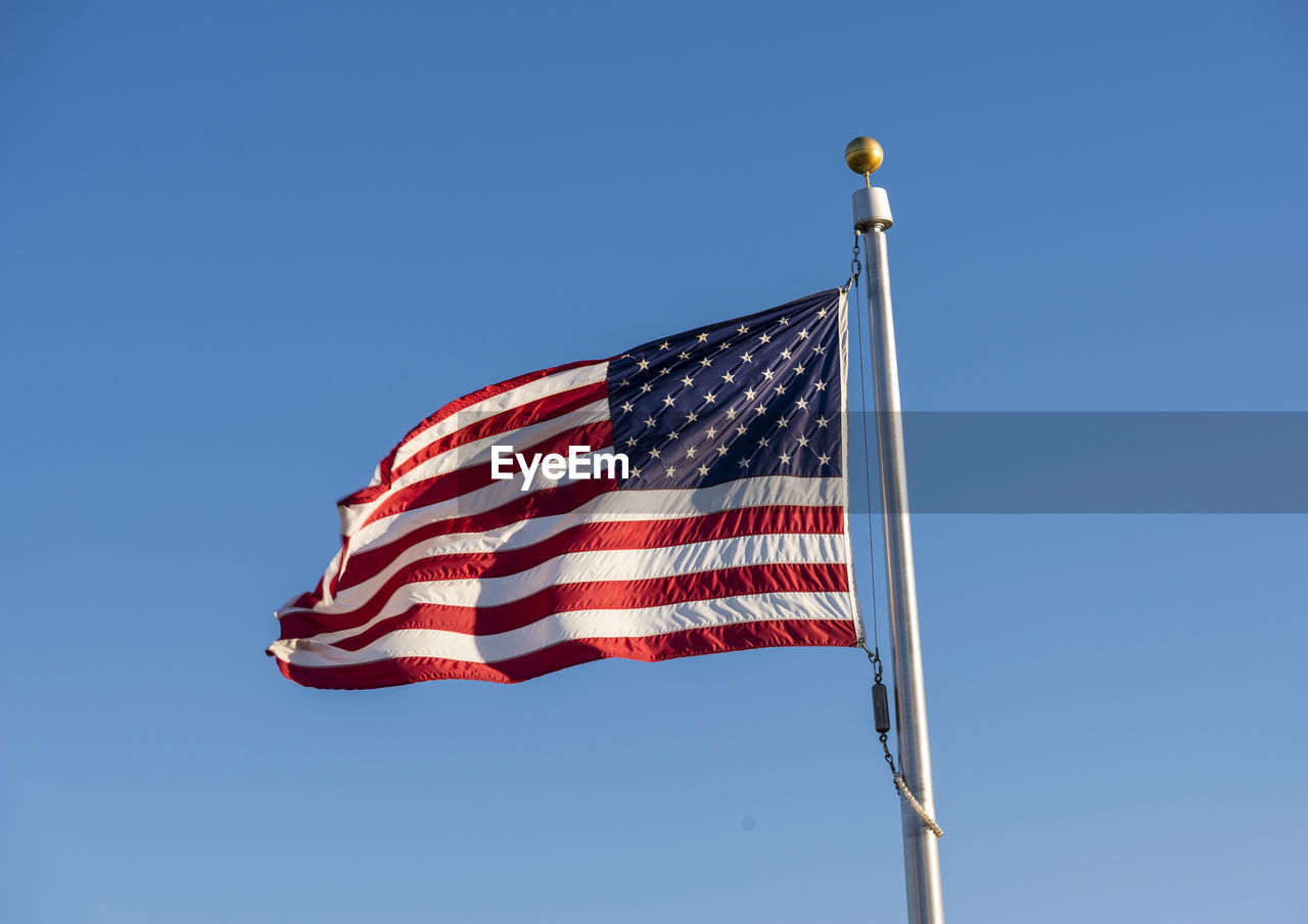 Low angle view of american flag against clear blue sky