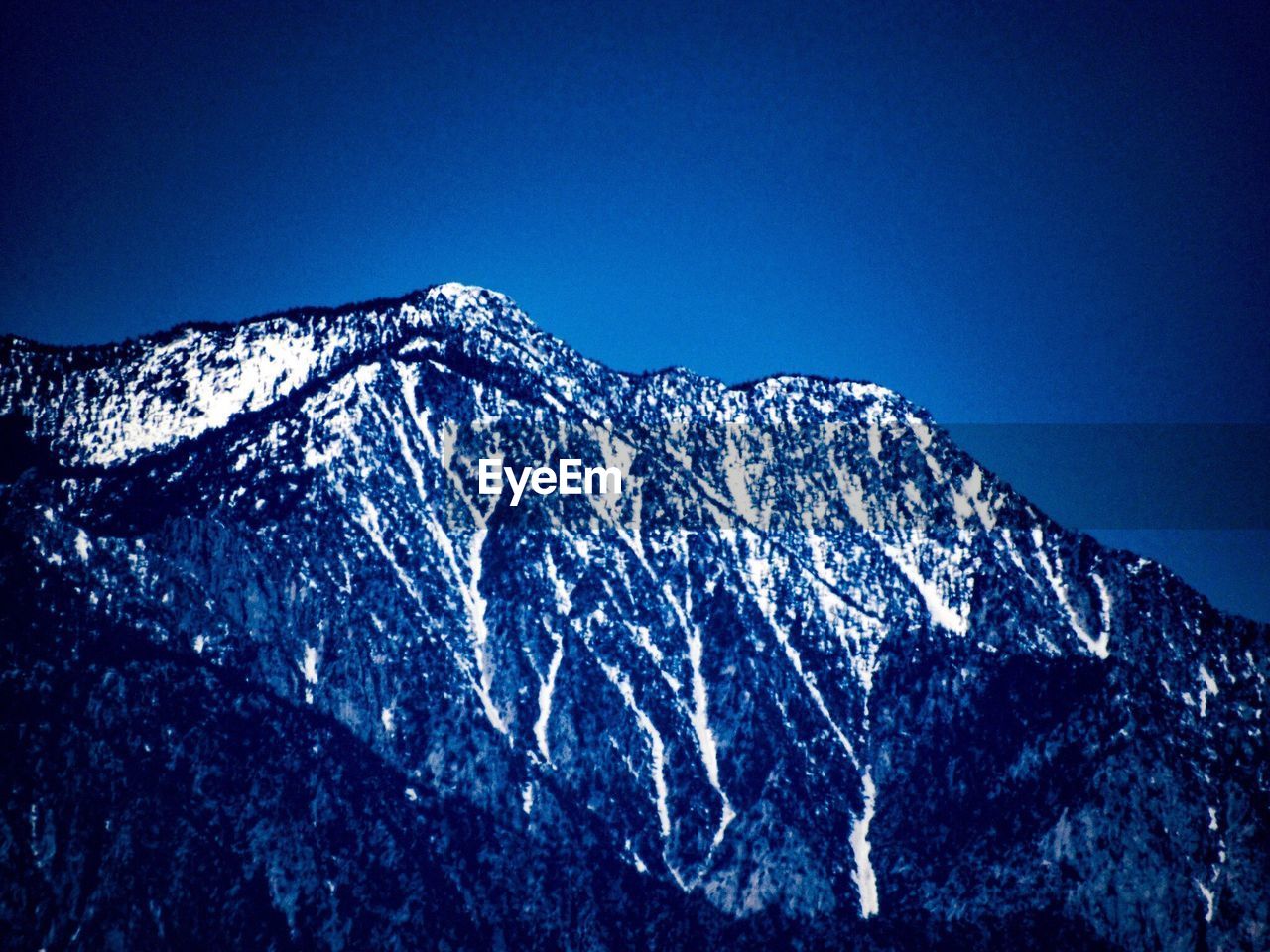 LOW ANGLE VIEW OF SNOWCAPPED MOUNTAIN AGAINST CLEAR SKY