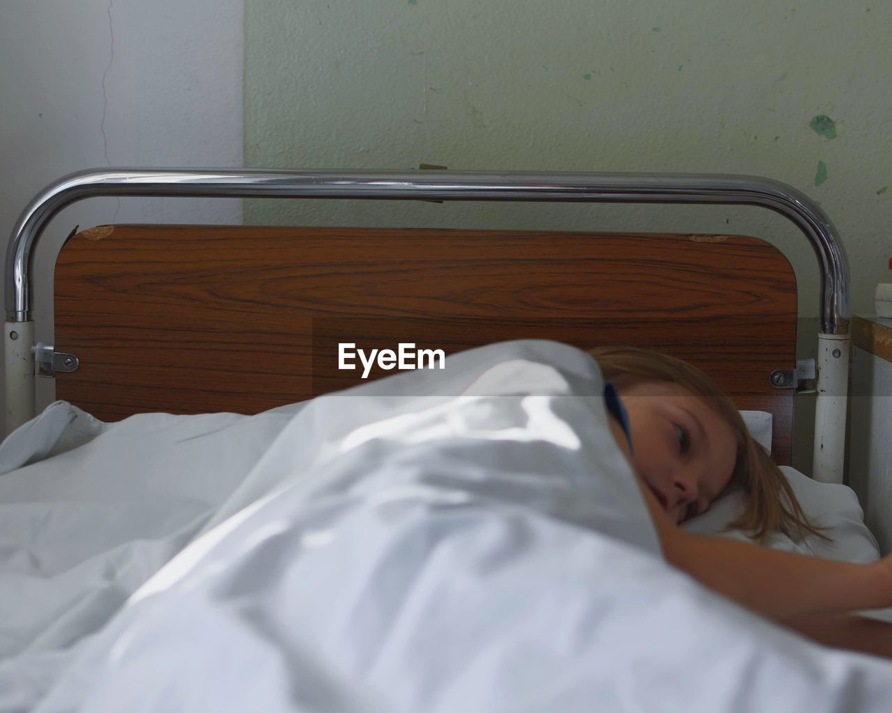 Portrait of kid lying in hospital bed