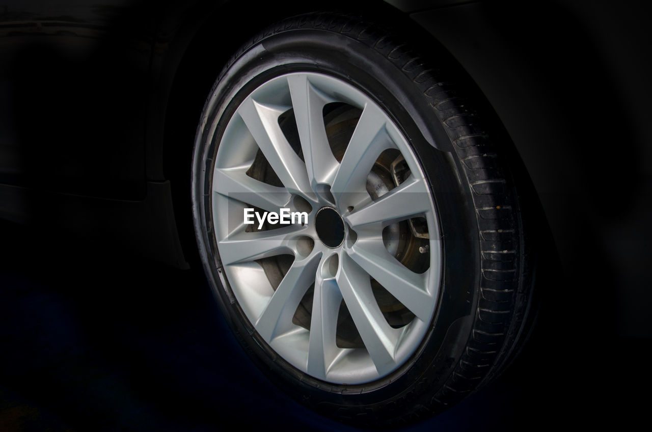 Close-up of car wheel against black background