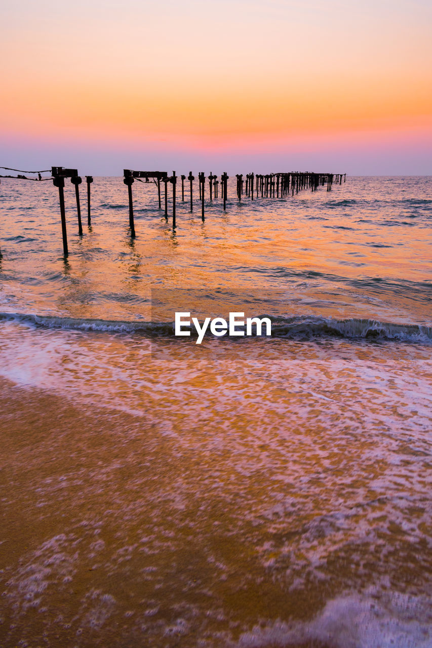 WOODEN POSTS IN SEA AGAINST SKY