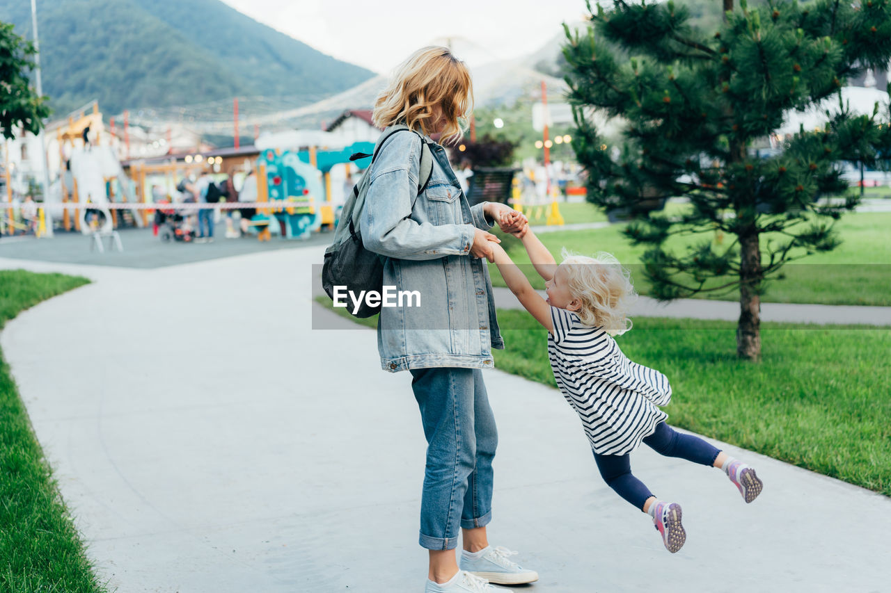 Mom twirls her daughter holding her hands, mom plays with her daughter. 