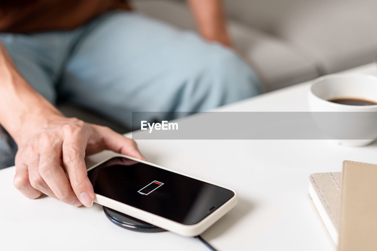 midsection of woman using mobile phone while sitting on table