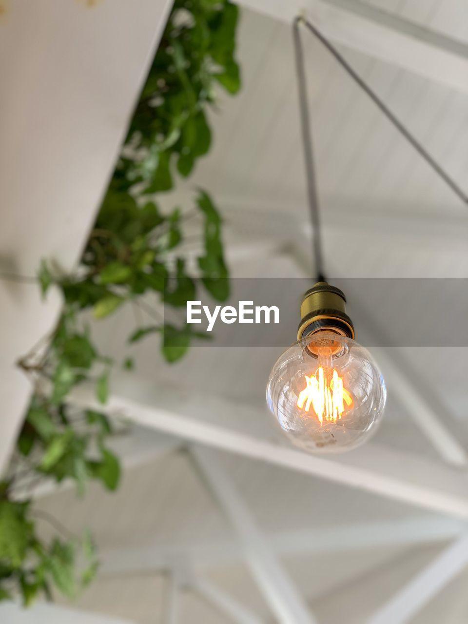 Low angle view of illuminated light bulb hanging on ceiling