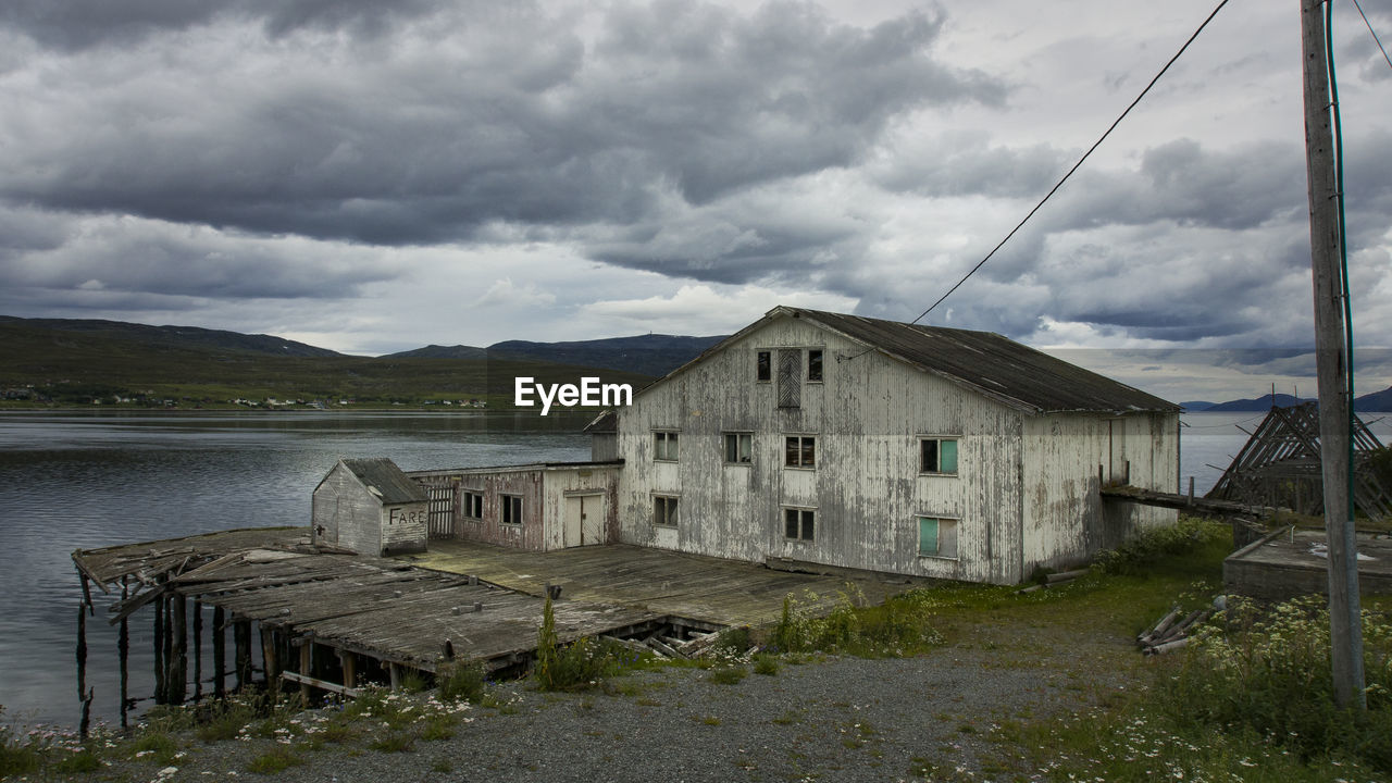 ABANDONED HOUSES BY LAKE AGAINST SKY