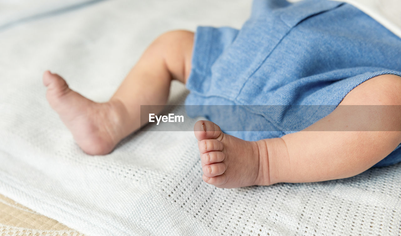 Low section of baby lying on bed