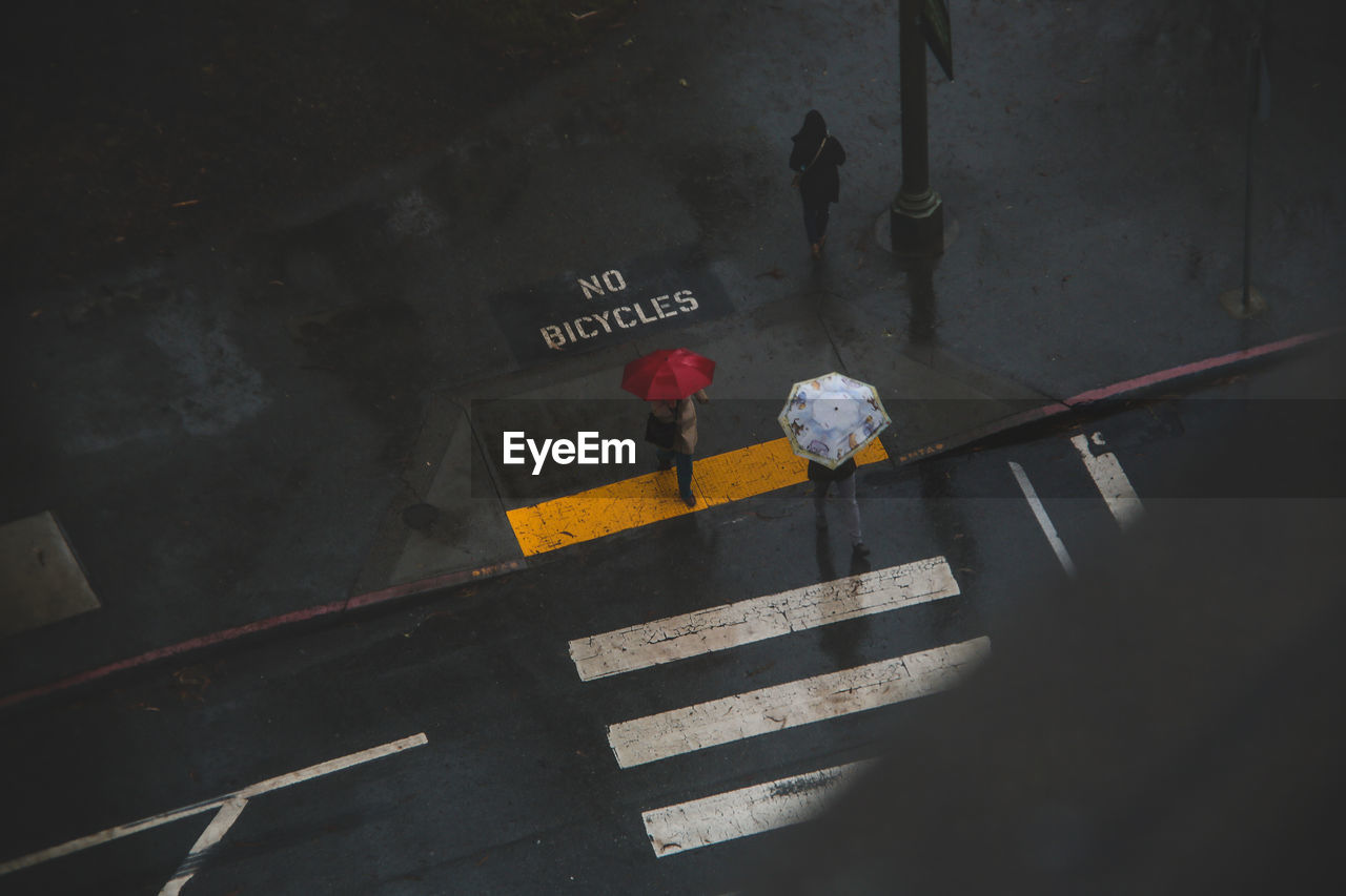 High angle view of people walking on street during rain