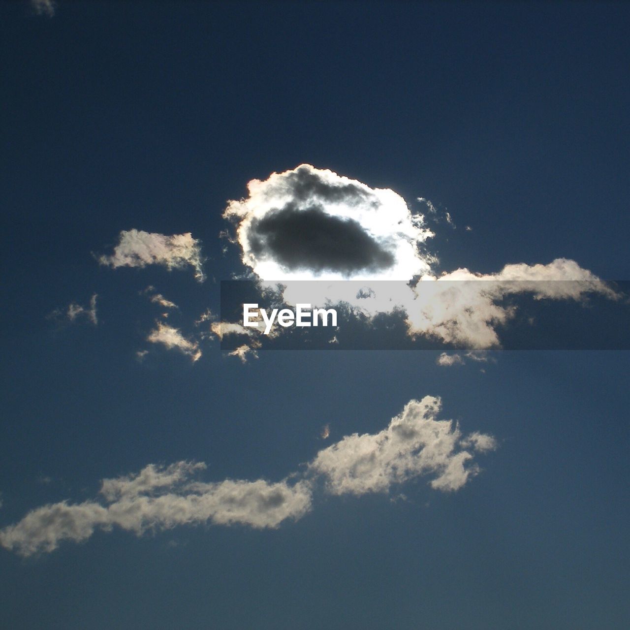 Low angle view sun shining behind cloud in sky