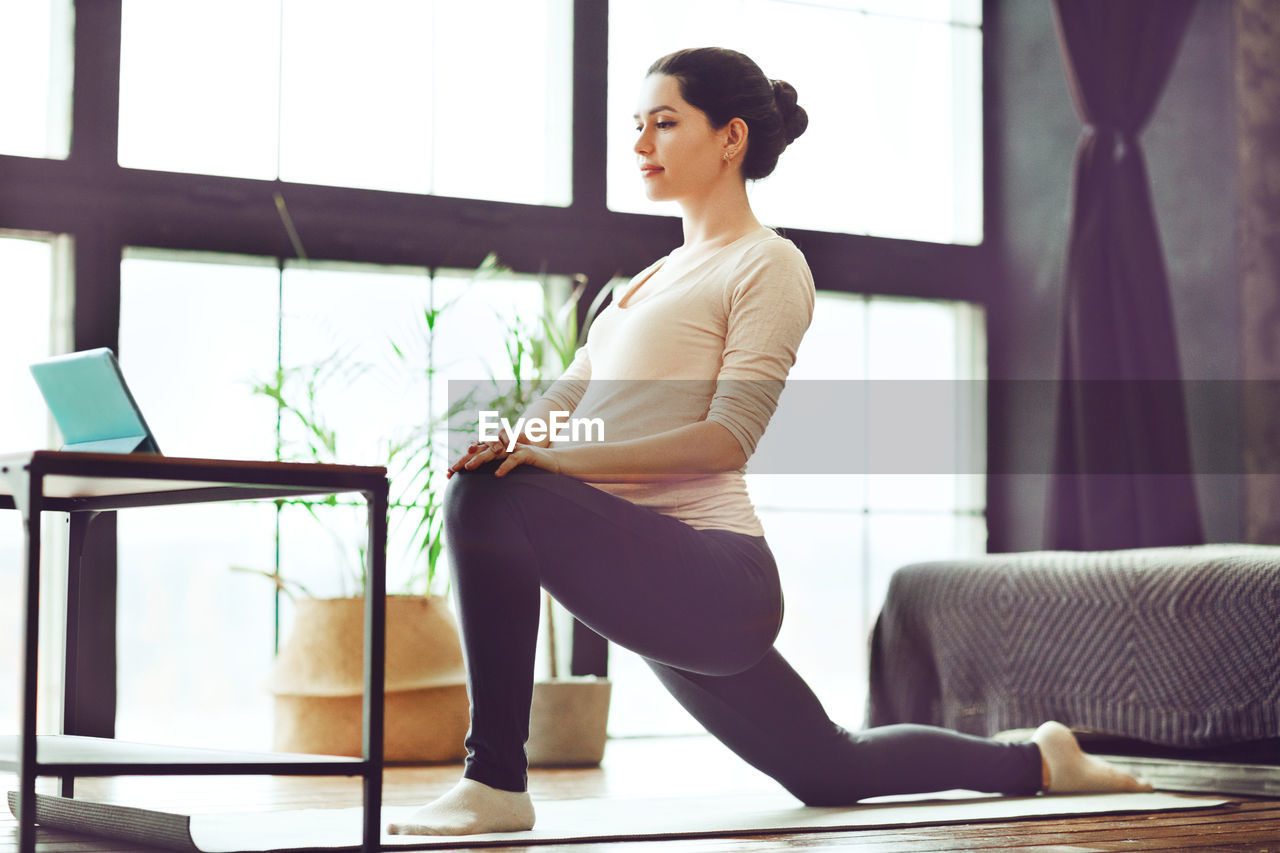 side view of young woman using laptop while sitting on sofa at home