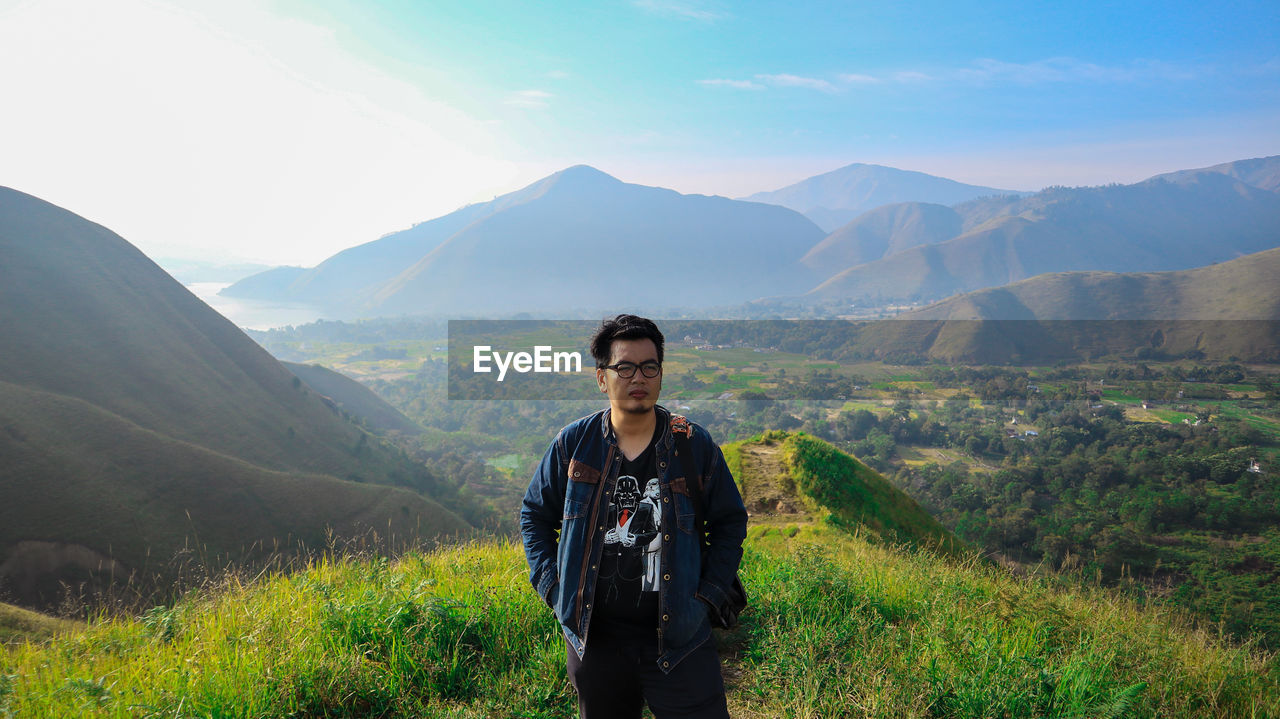 Young man standing on mountain against sky