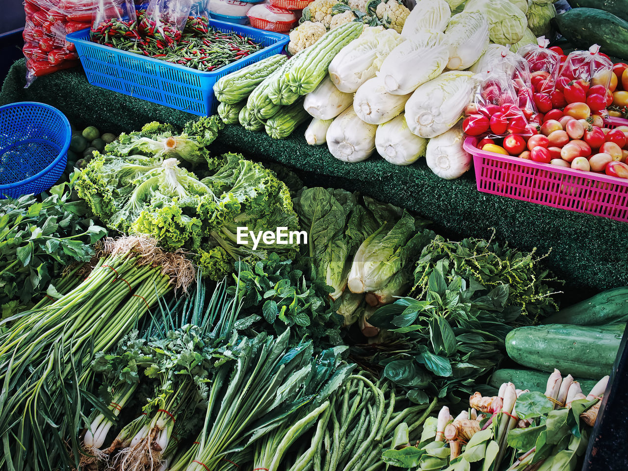 Pile of various kinds of fresh green herbal vegetables for sale at market stall