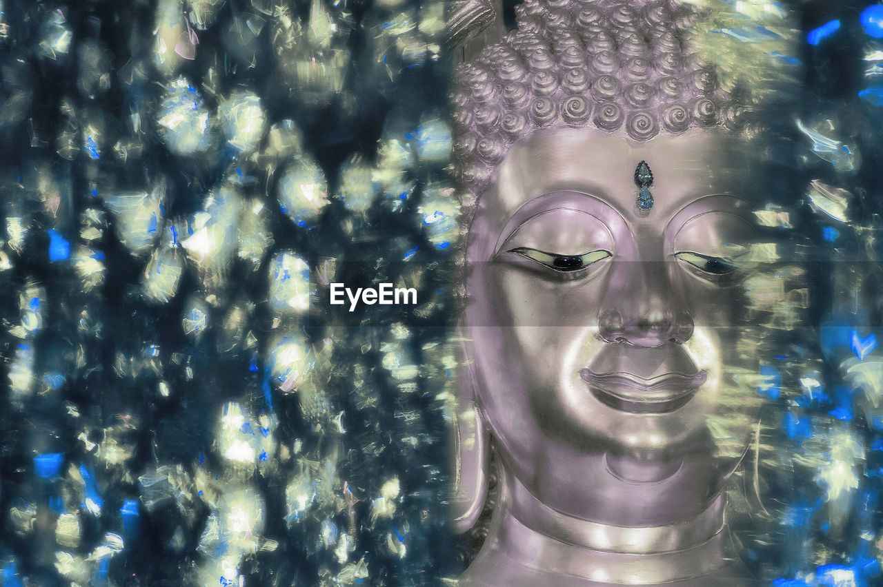 Close-up of buddha statue seen through glass