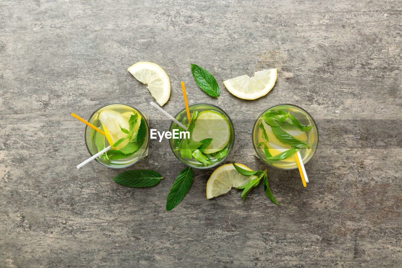 green, leaf, food and drink, high angle view, yellow, food, freshness, citrus fruit, no people, healthy eating, fruit, directly above, still life, lime, wellbeing, flower, nature, plant, plant part, slice, produce, lemon, gray, drinking glass, glass, outdoors, drink