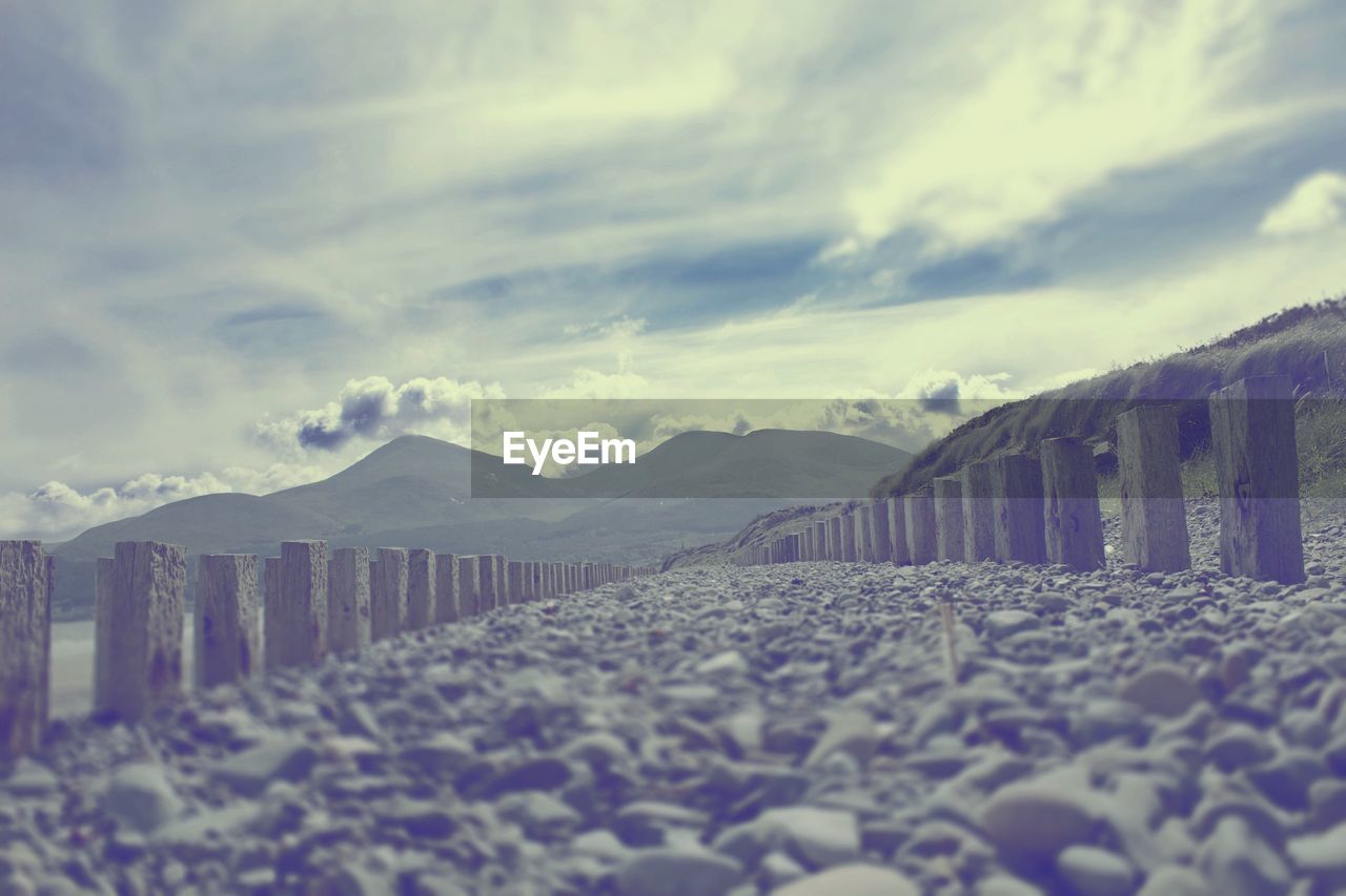 Surface level view of pebbles at beach against cloudy sky at murlough bay