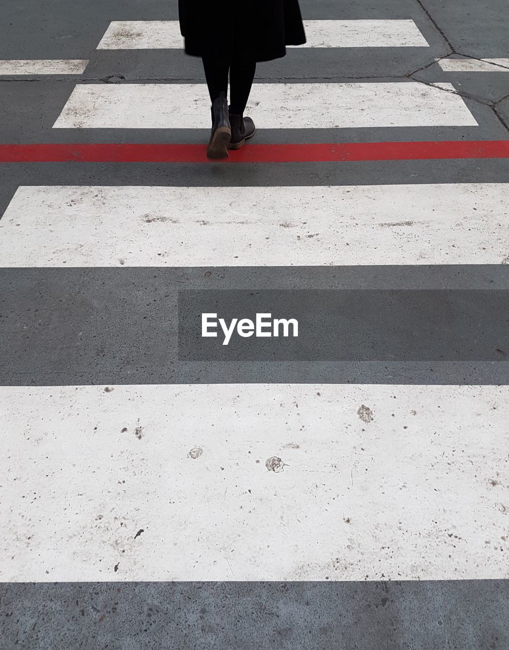 Low section of woman crossing on zebra crossing