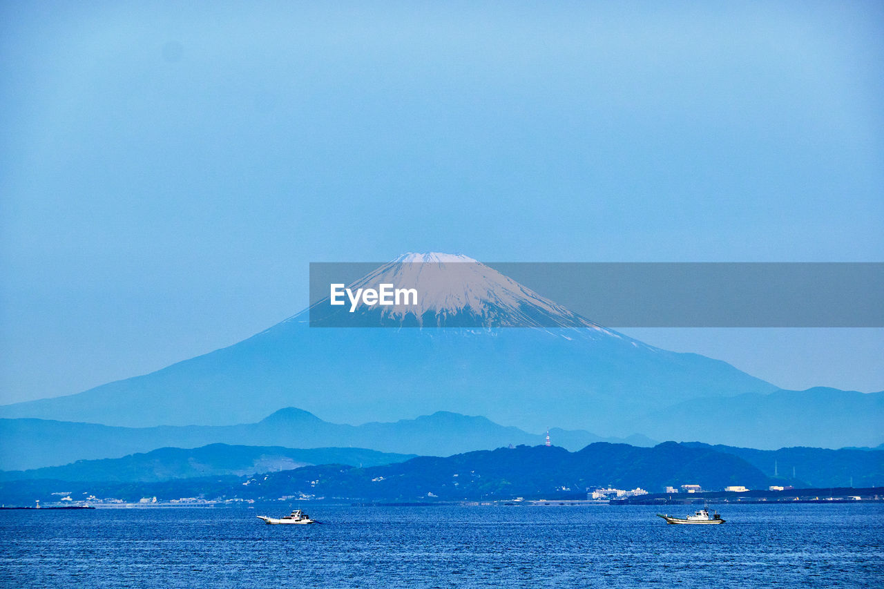 Scenic view of sea and snowcapped mountain against clear sky