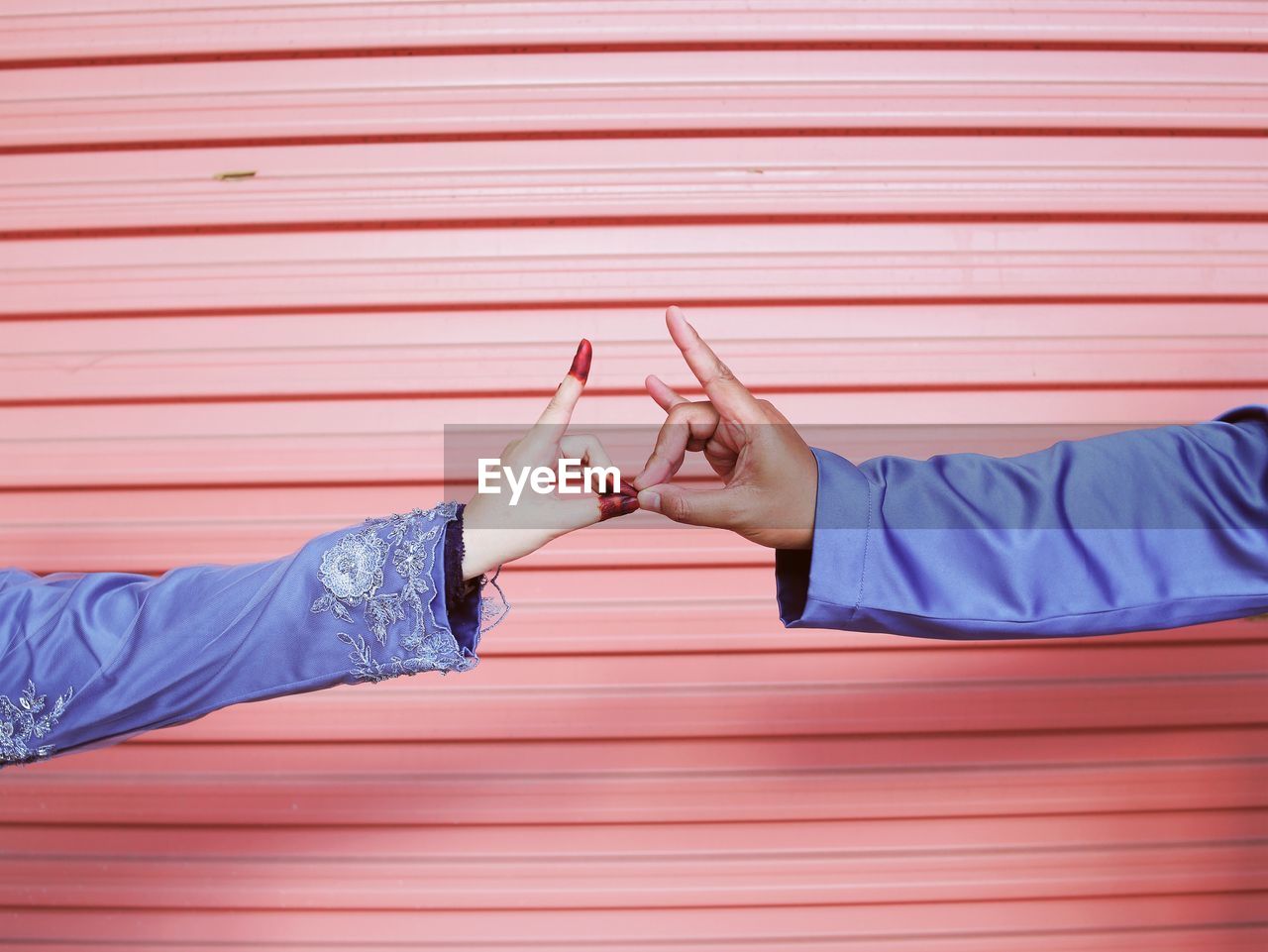 Cropped image of couple joining hands against shutter