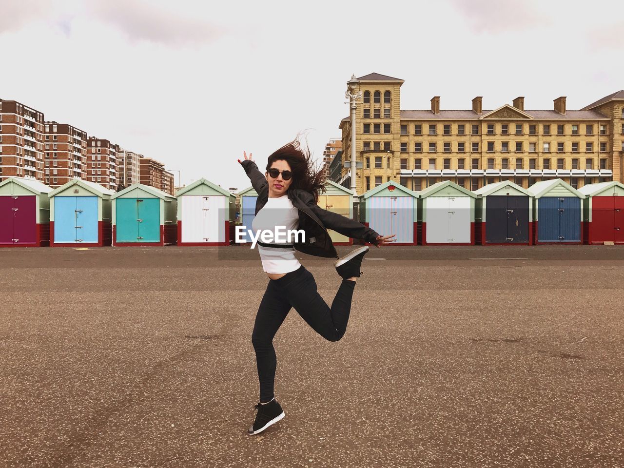 Full length of woman dancing on street against beach huts in city