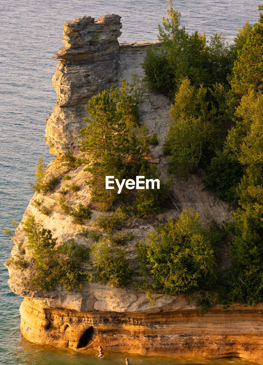 Two swimmers at the base of miners castle in unusually calm lake superior waters.