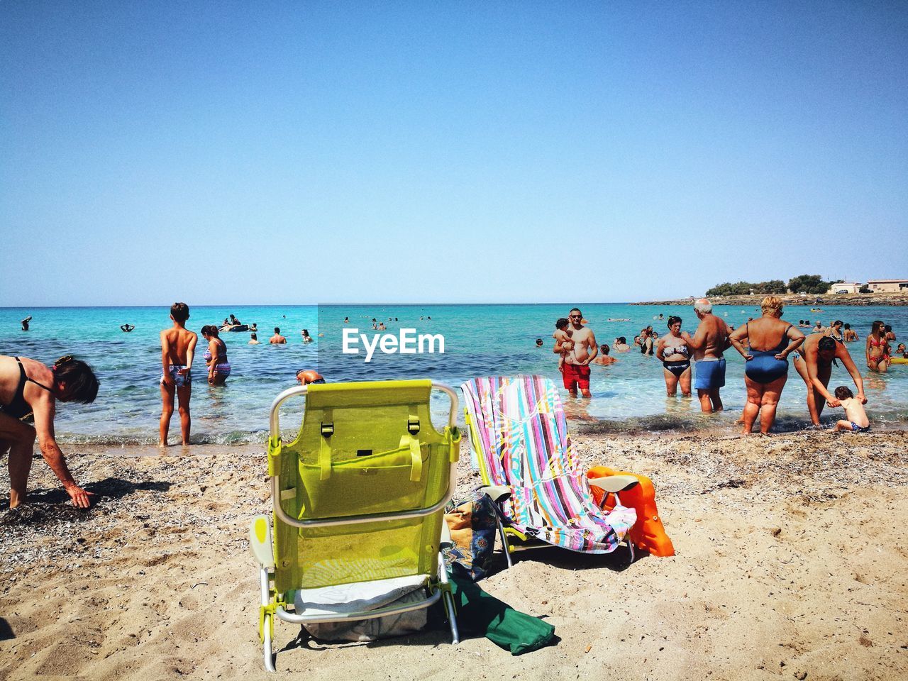 People at beach against clear blue sky