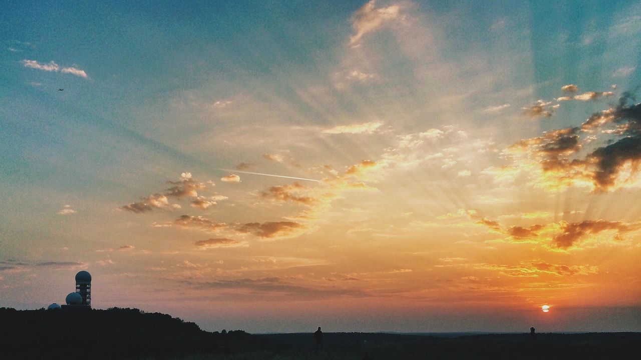 Scenic view of silhouette field against orange sky