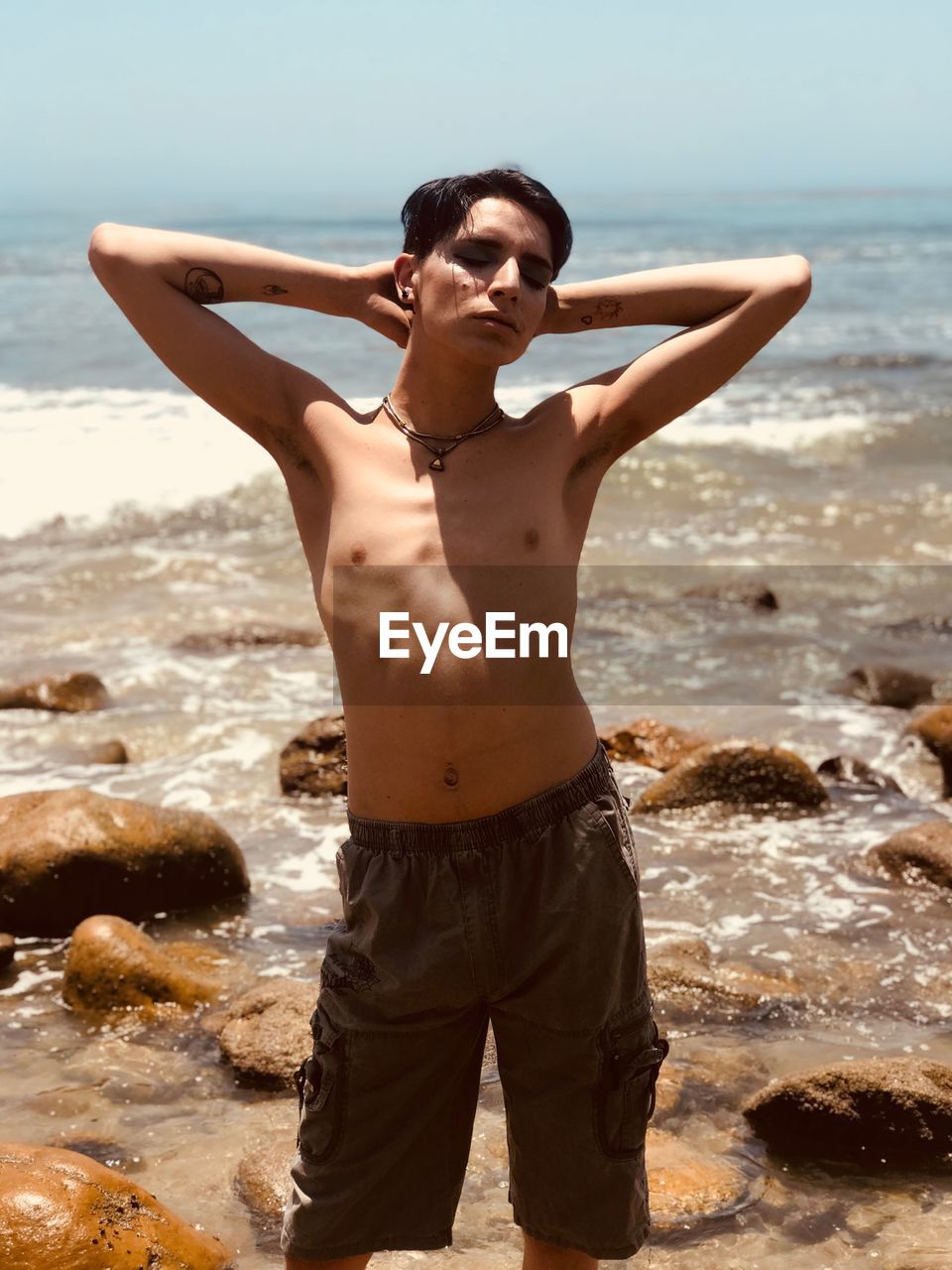 Shirtless gay man standing at beach