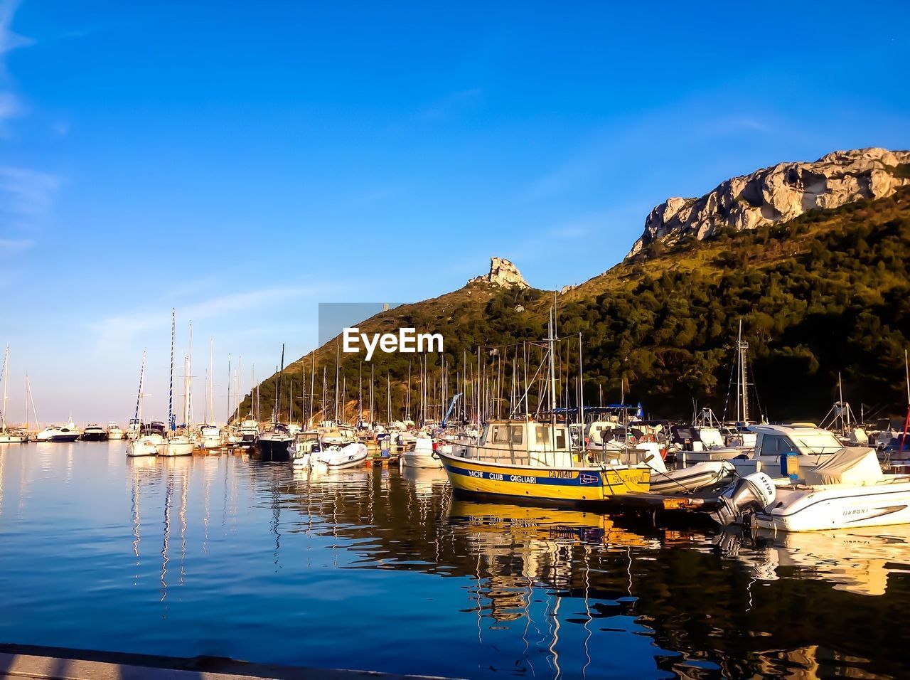 Boats at port on sea against blue sky