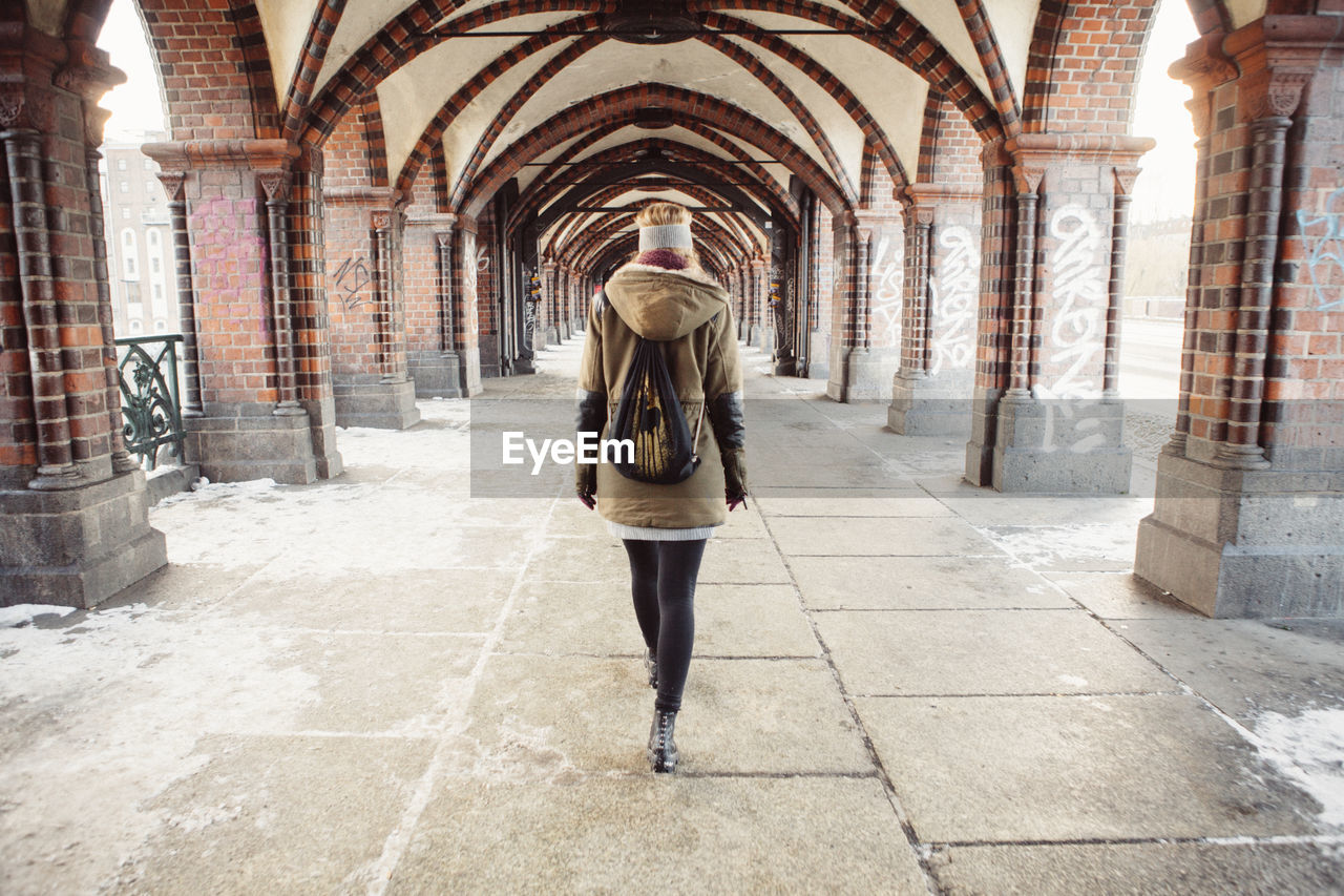 Rear view of young woman walking at railroad station platform during winter